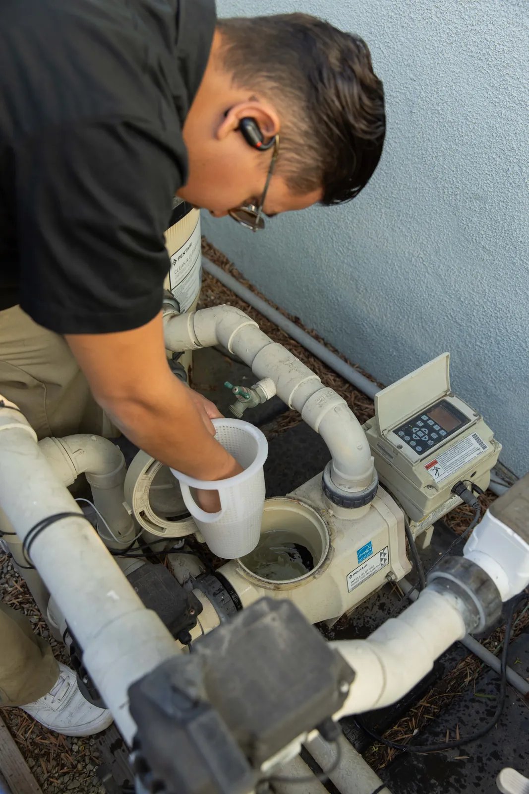An Adam's technician inspecting pool pump and filter equipment